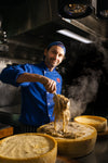 Federico serving pasta on a cheese wheel