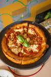 Small pizza with a basil leaf on a black plate against a colorful background